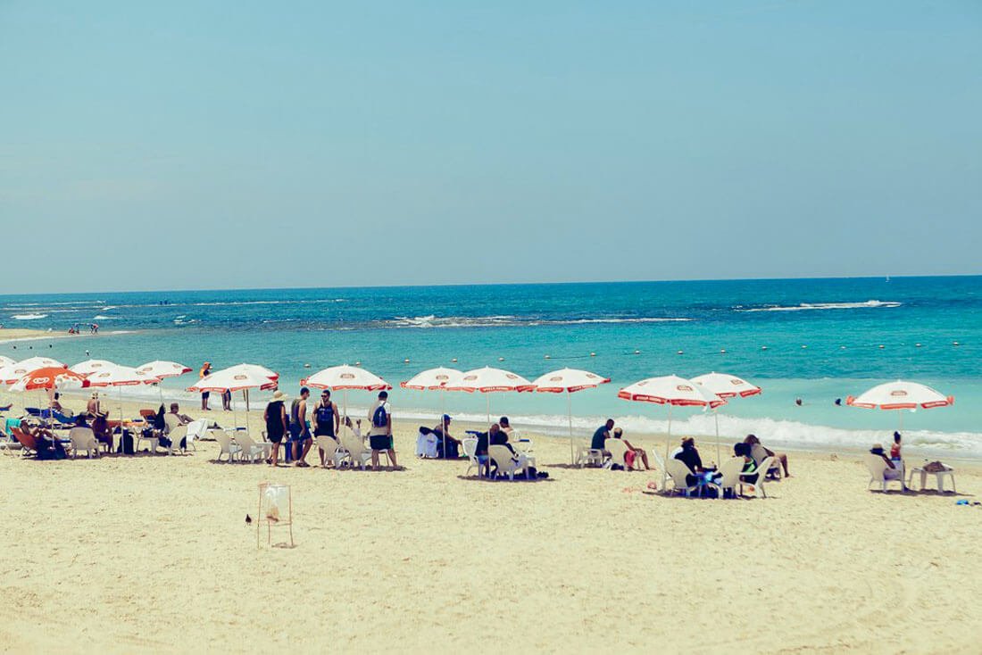 Vacationers on high chairs under umbrellas on Ajami beach Ajami or Jaffa Beach