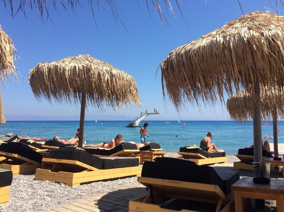 Vacationers on the sandy and pebble beach of Elli in Rhodes Sun beds with umbrellas on the beach