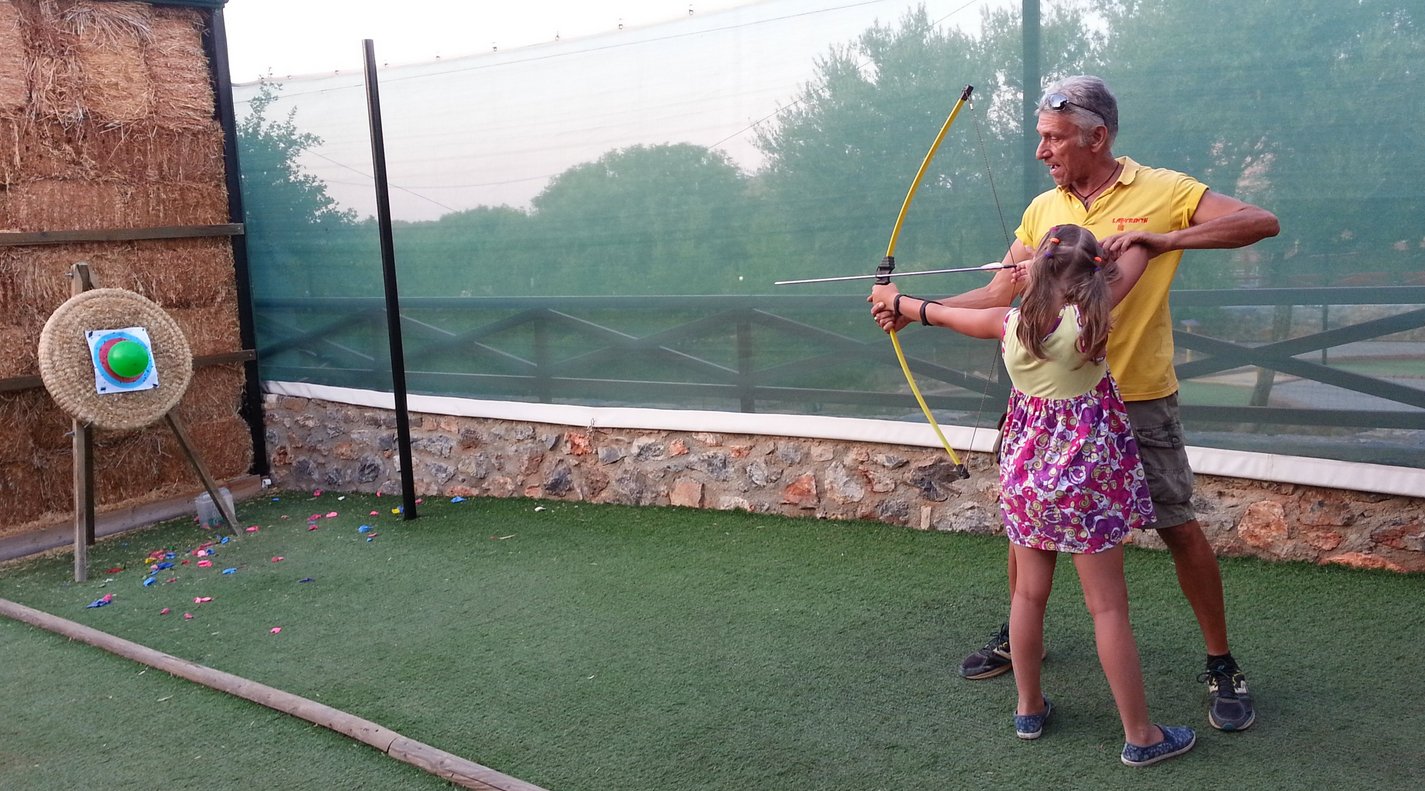 An instructor teaches a girl archery in the Labyrinth Park, Hersonissos Archery Game