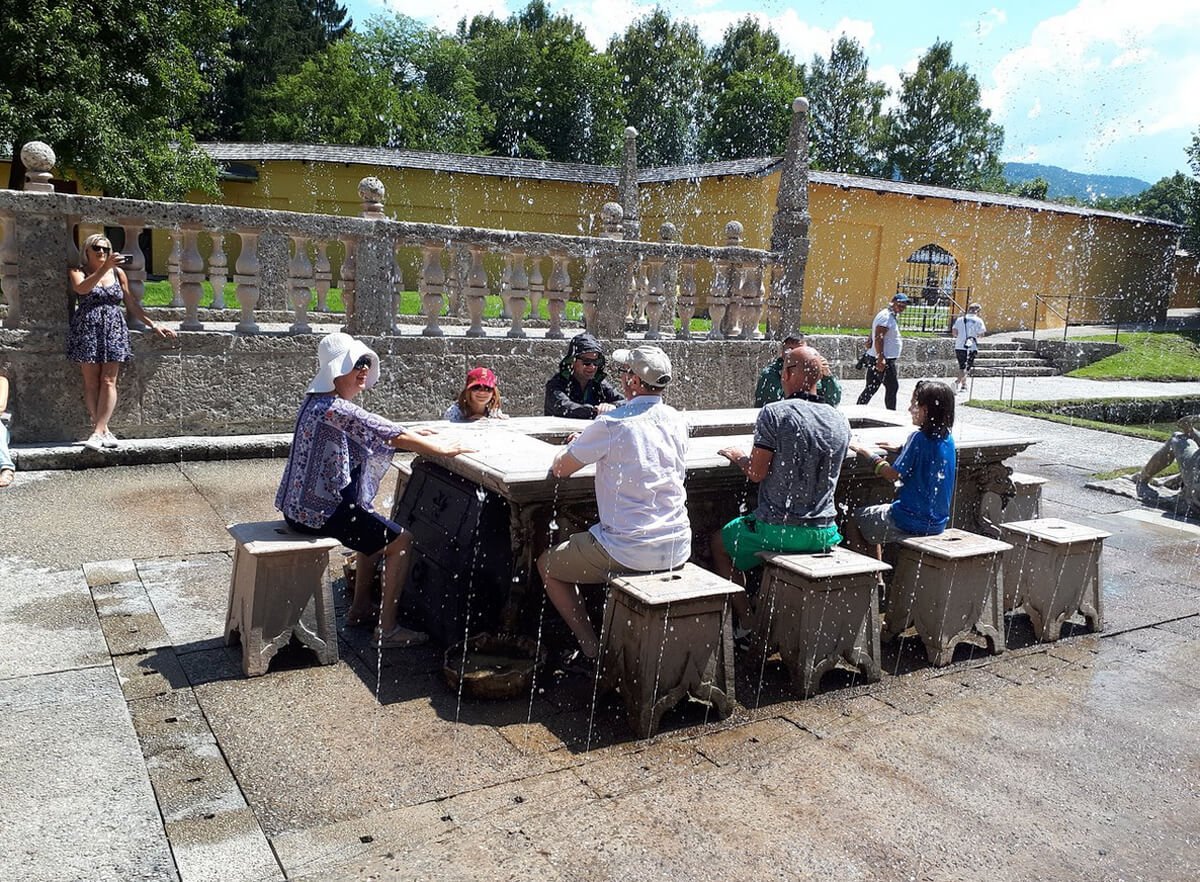 People sit on stools around a table with fountains in Helburnn Palace Park Stone countertop