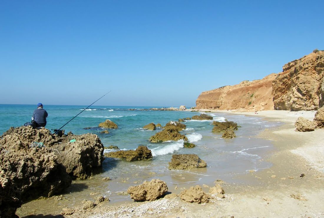 Fisherman on the cliff of Blue Bay beach in Netanya Blue Bay Beach