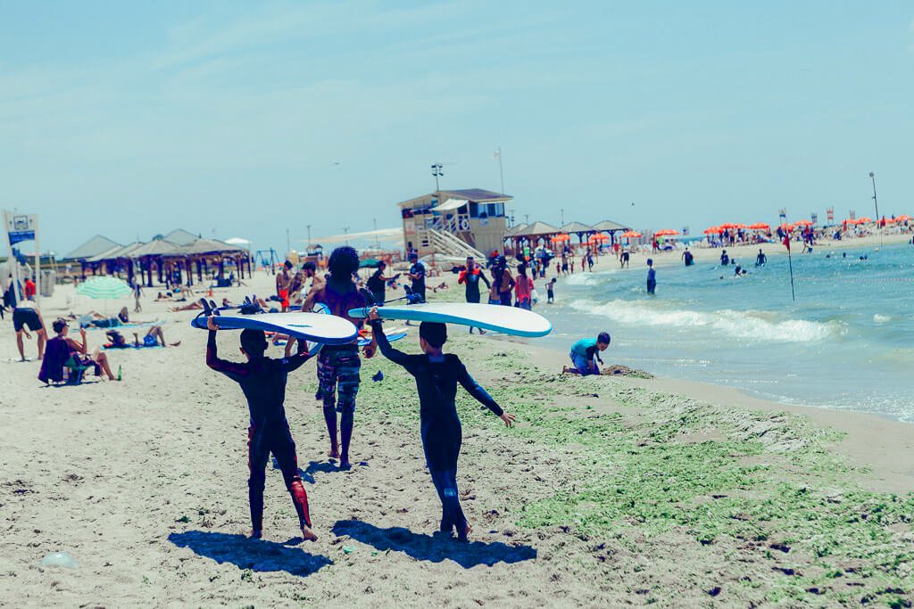 Teenagers carry surfboards at Tel-Baruh beach Tel-Baruh beach
