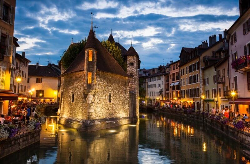 An island castle in Annecy with a sidewalk in the evening Annecy Island castle in the evening