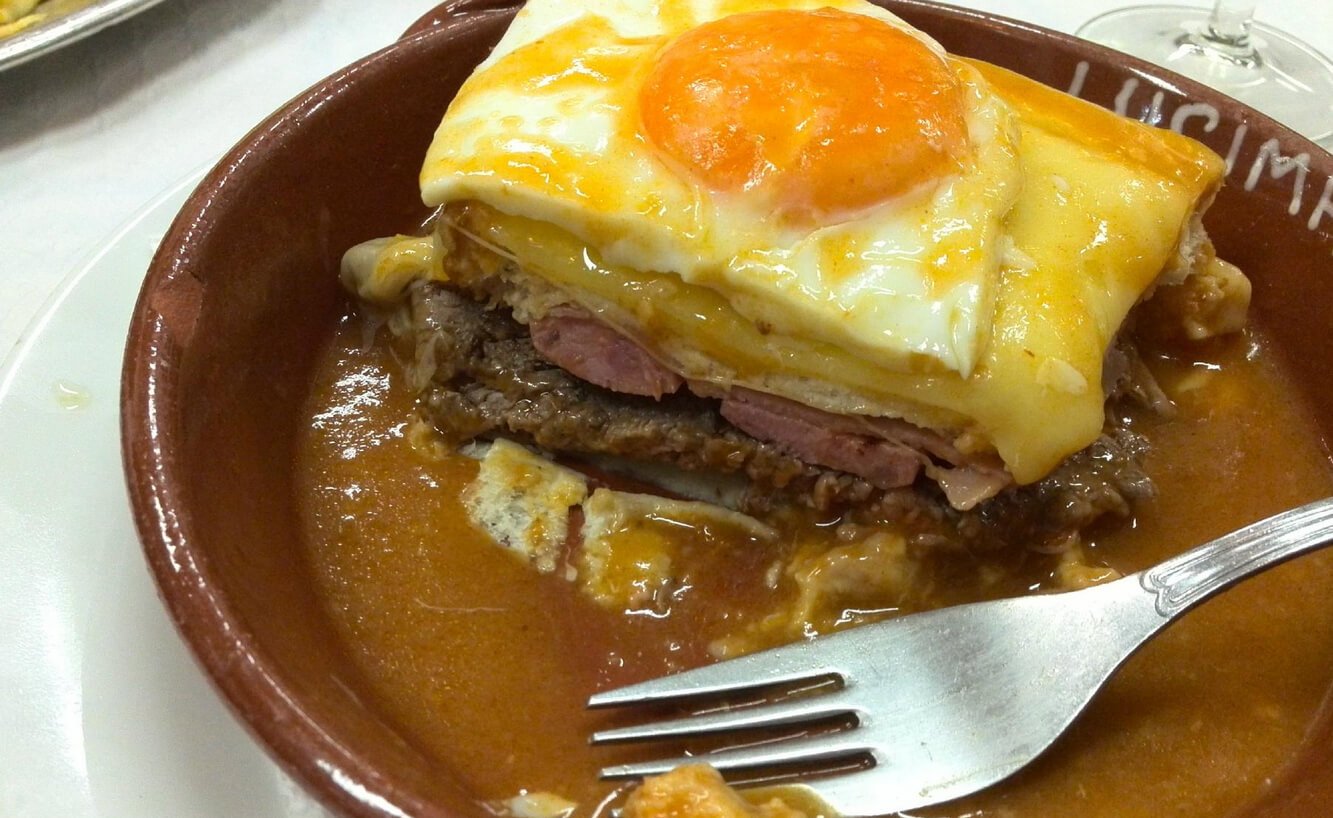 Photo of a Portuguese sandwich called Francesinha topped with a fried egg eye The famous "Portuguese sandwich" Francesinha