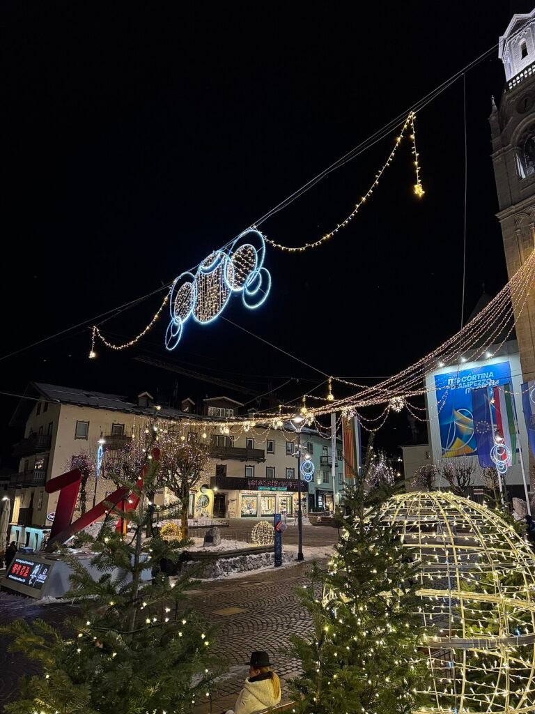 Cortina d'Ampezzo town centre at night decorated with Christmas lights, illuminated trees and the church bell tower