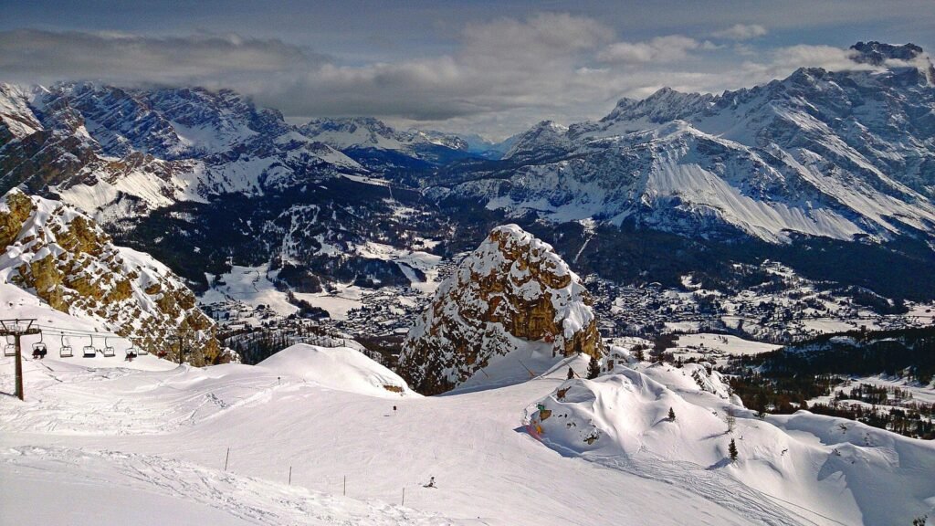 Snowy slopes and a chairlift above the Ampezzo valley, with Cortina d'Ampezzo and the Dolomites behind, in March