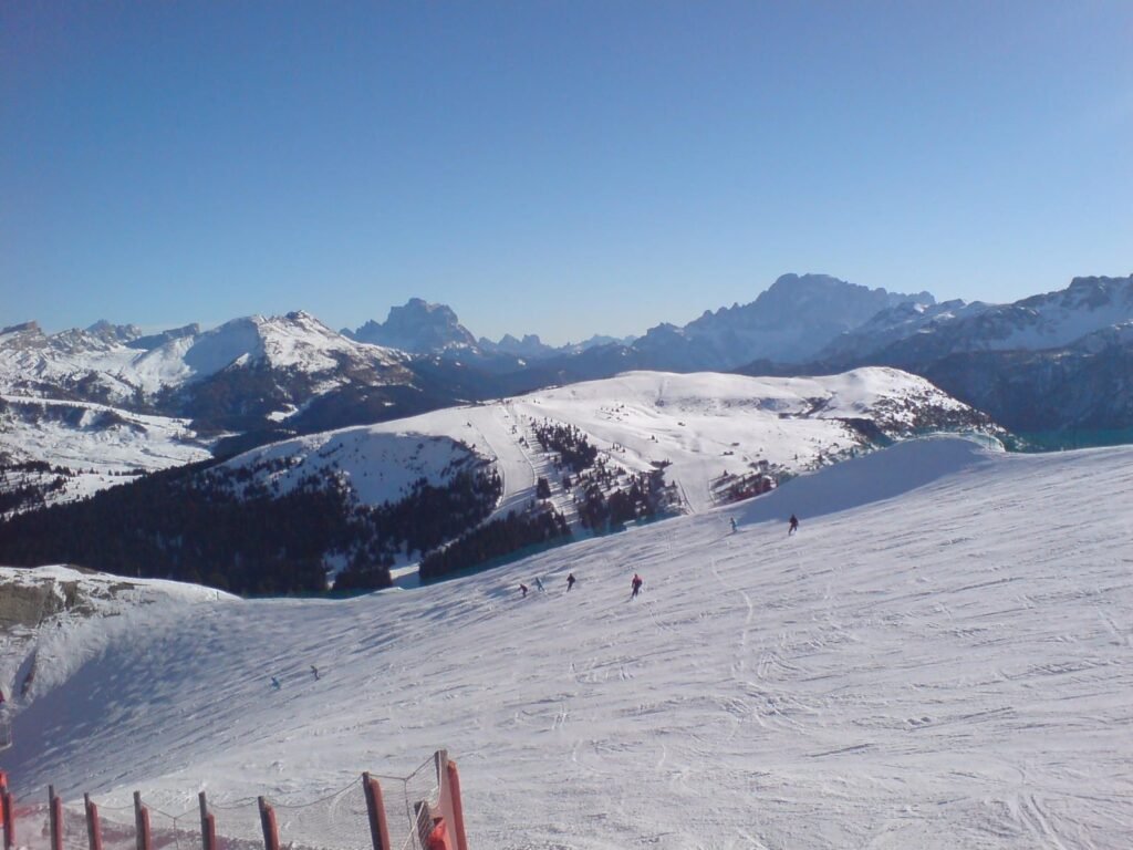 Skiers on a wide groomed piste on Lagazuoi with Monte Pelmo and the Civetta on the horizon