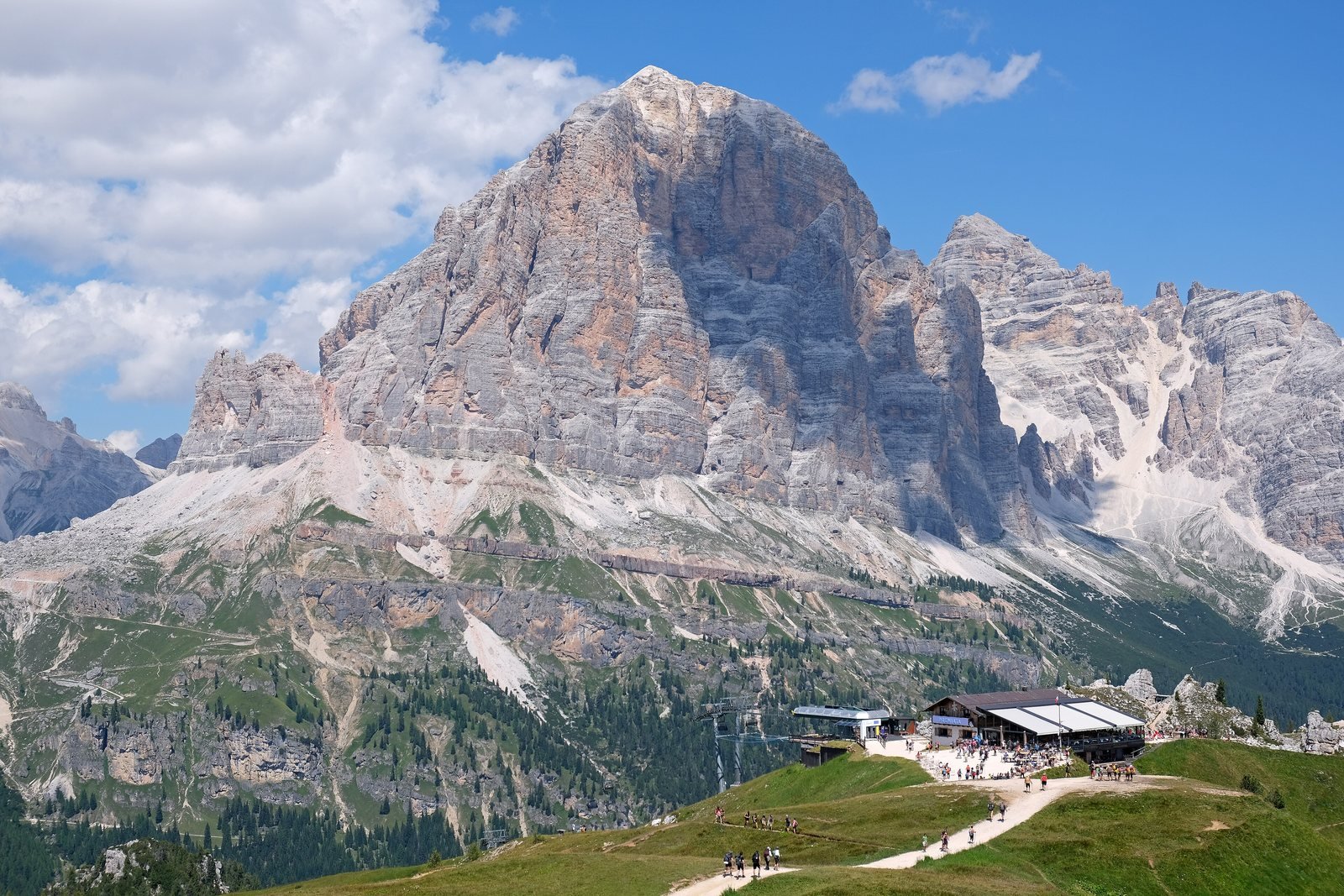 Tofana di Rozes rising above Rifugio Scoiattoli and green summer meadows near Cortina d'Ampezzo